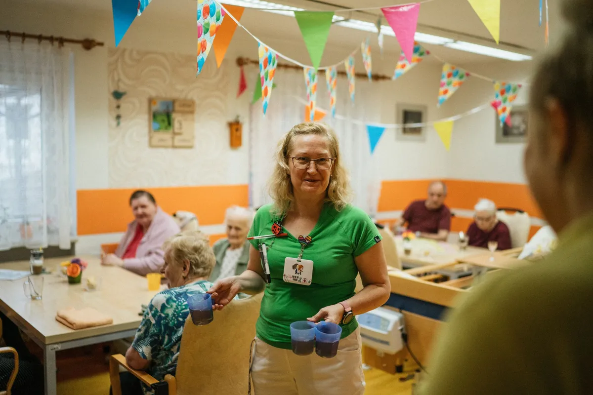 Soignante servant à boire à des résidents âgés dans une maison de retraite conviviale