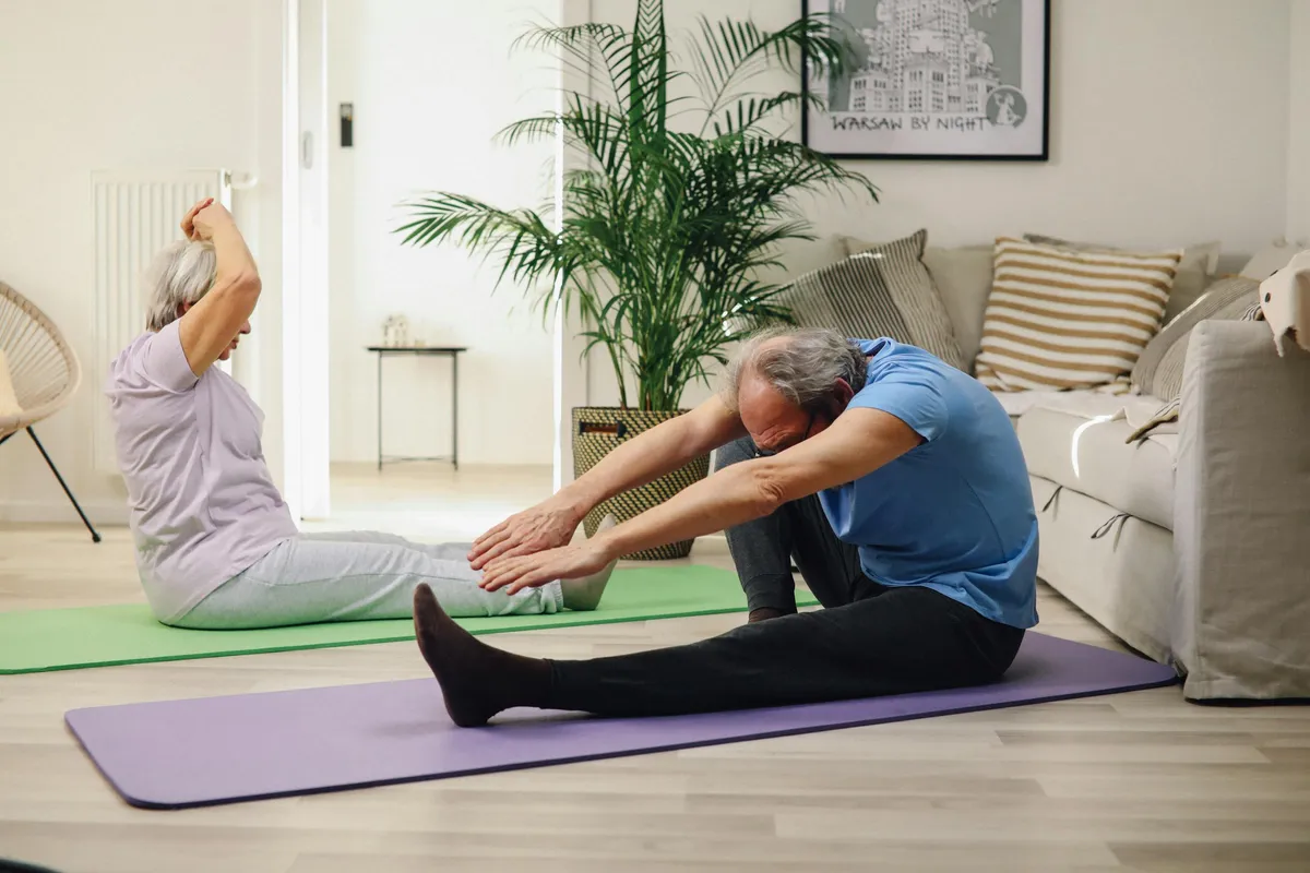 Couple de seniors pratiquant le yoga à la maison pour entretenir leur forme